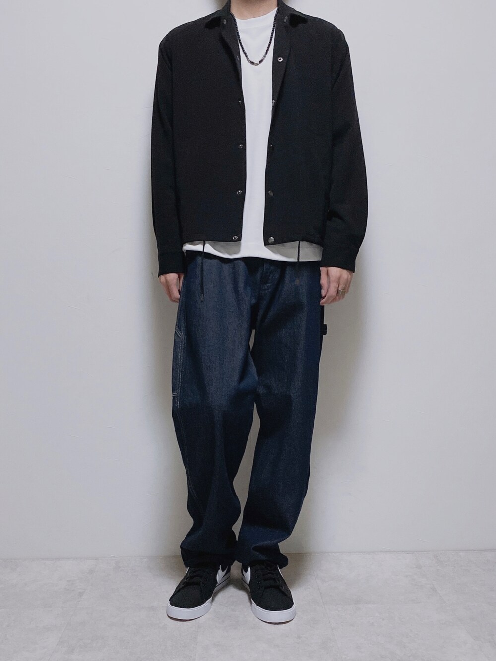 ブラック系のブルゾン、ブルー系のデニムパンツ、ブラック系のスニーカーを着用したメンズの秋コーディネートの1枚目の写真