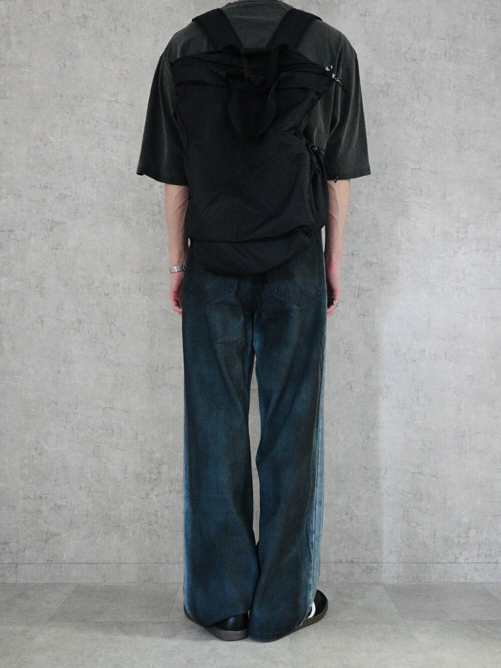 ブラック系のバックパック/リュック、ブラック系のTシャツ/カットソー、ブラック系のデニムパンツを着用したメンズの春コーディネートの1枚目の写真