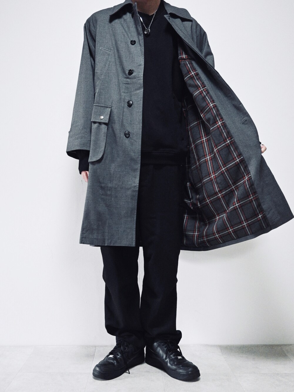 グレー系のステンカラーコート、ブラック系のスウェット、ブラック系のパンツを着用したメンズの冬コーディネートの1枚目の写真