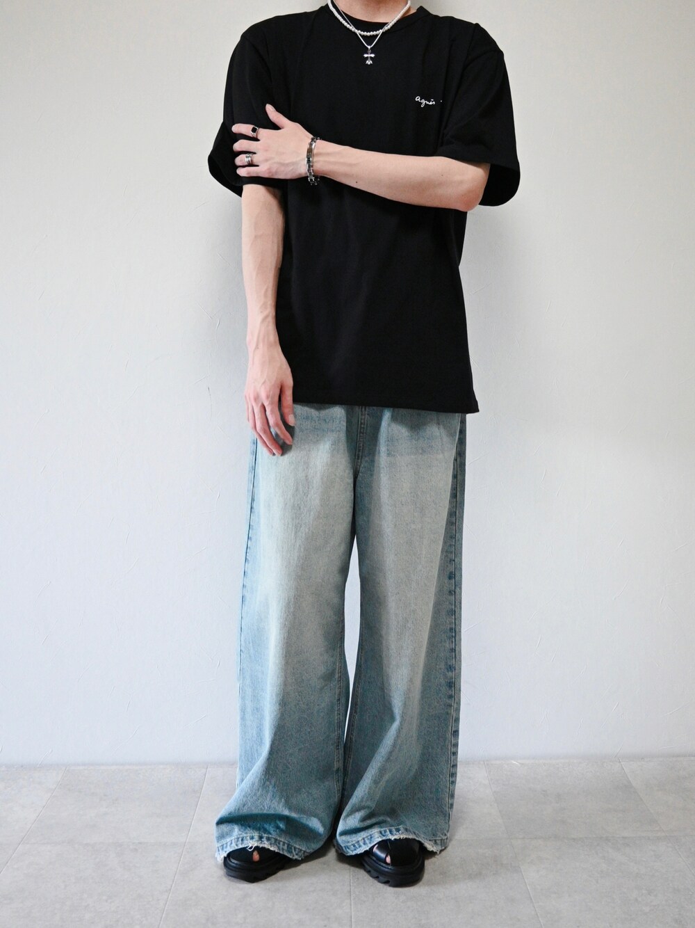 ブラック系のTシャツ/カットソー、ブルー系のデニムパンツ、シルバー系のブレスレットを着用したメンズの夏コーディネートの1枚目の写真
