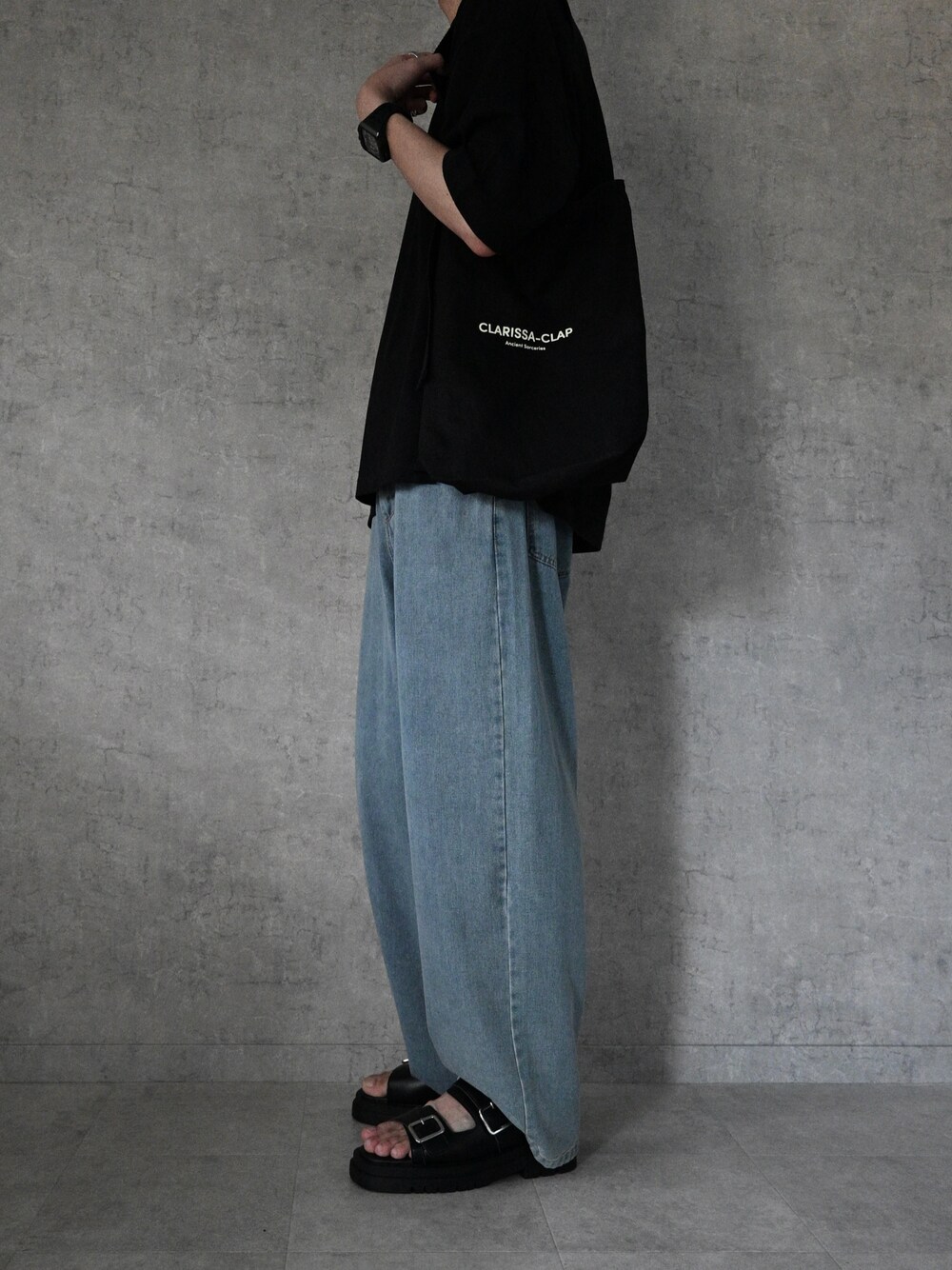 ブラック系のサンダル、ブラック系のTシャツ/カットソー、ブルー系のデニムパンツを着用したメンズの夏コーディネートの1枚目の写真