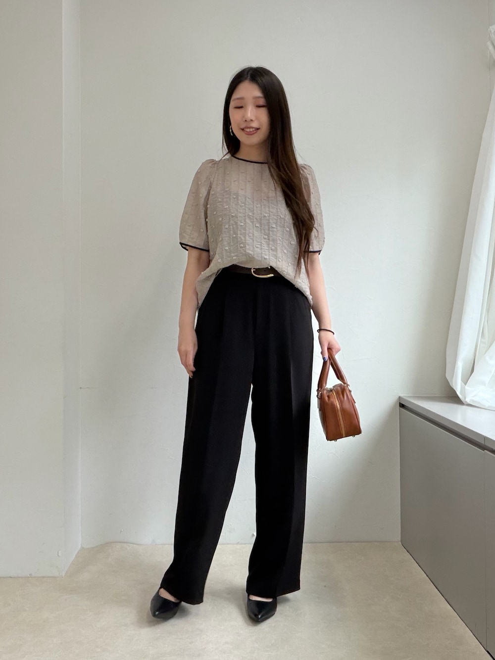 ベージュ系のシャツ/ブラウス、ブラック系のスラックス、ブラック系のパンプスを着用したレディースの春コーディネートの1枚目の写真