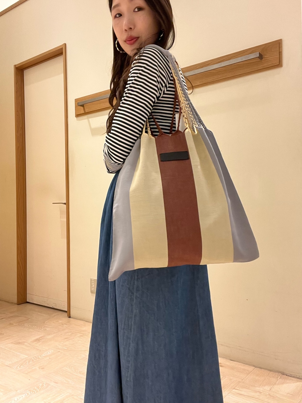 ブラウン系のトートバッグ、ホワイト系のTシャツ/カットソー、ブルー系のワンピースを着用したレディースの春コーディネートの1枚目の写真