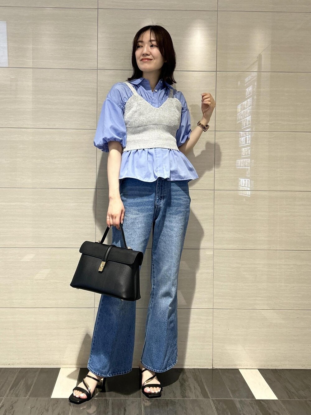 ブラック系のハンドバッグ、ブルー系のデニムパンツ、ブラック系のサンダルを着用したレディースの春コーディネートの1枚目の写真