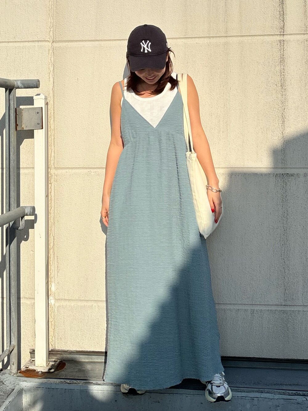 ホワイト系のタンクトップ、ブルー系のワンピース、ホワイト系のスニーカーを着用したレディースの春コーディネートの1枚目の写真