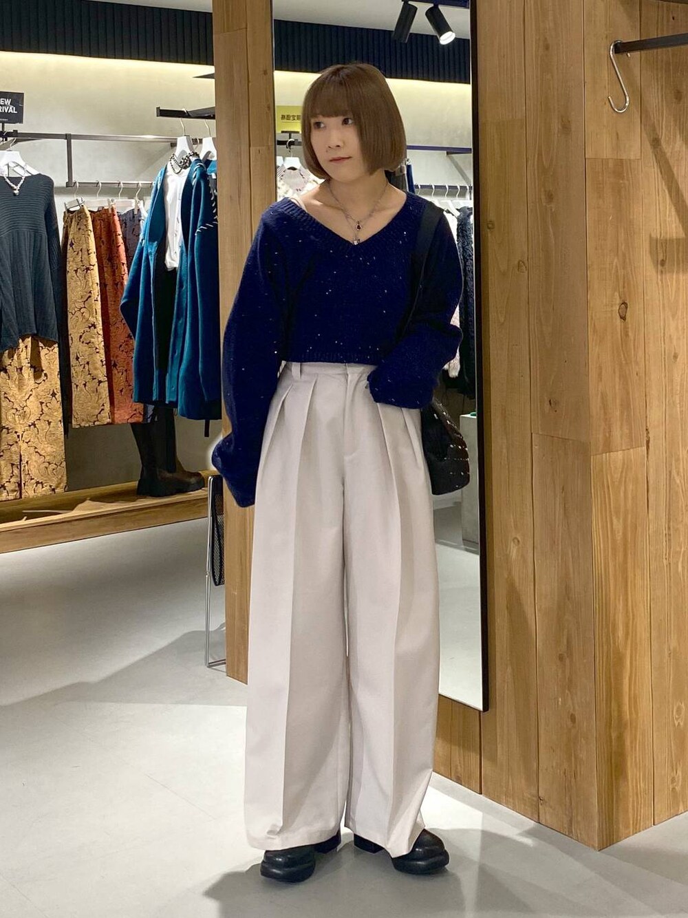 ホワイト系のキャミソール、ブラック系のブーツ、ベージュ系のスラックスを着用したレディースの冬コーディネートの1枚目の写真