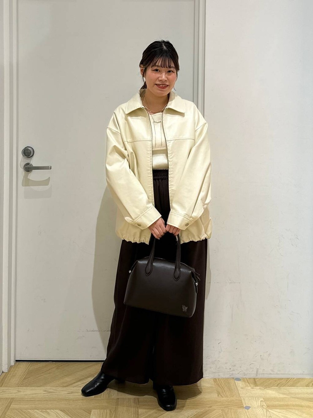 ブラック系のブーツ、ブラウン系のショルダーバッグ、ホワイト系のブルゾンを着用したレディースの冬コーディネートの1枚目の写真