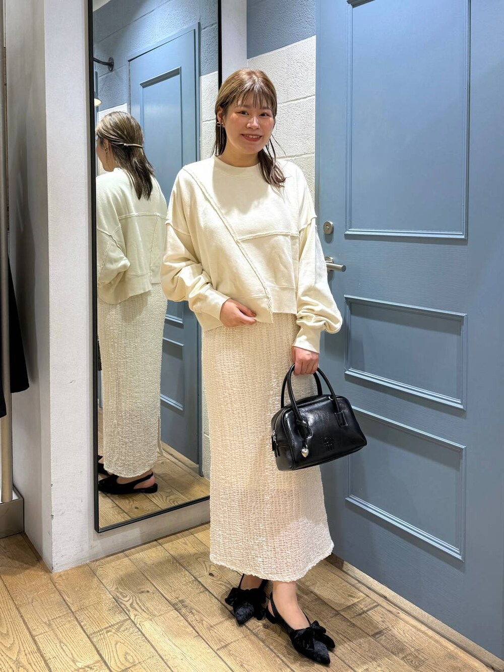 ブラック系のパンプス、ホワイト系のスウェット、ブラック系のボストンバッグを着用したレディースの秋コーディネートの1枚目の写真