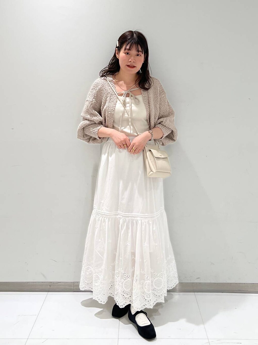 ホワイト系のスカート、ホワイト系のショルダーバッグ、その他のパンプスを着用したレディースの冬コーディネートの1枚目の写真