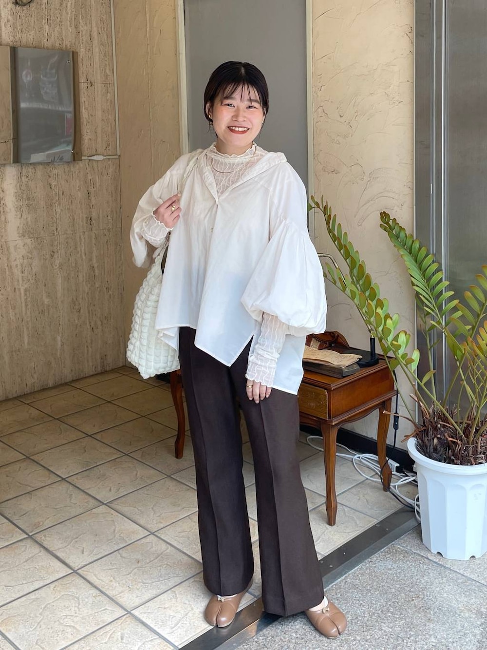 ホワイト系のショルダーバッグ、ホワイト系のTシャツ/カットソー、ブラウン系のスラックスを着用したレディースの秋コーディネートの1枚目の写真