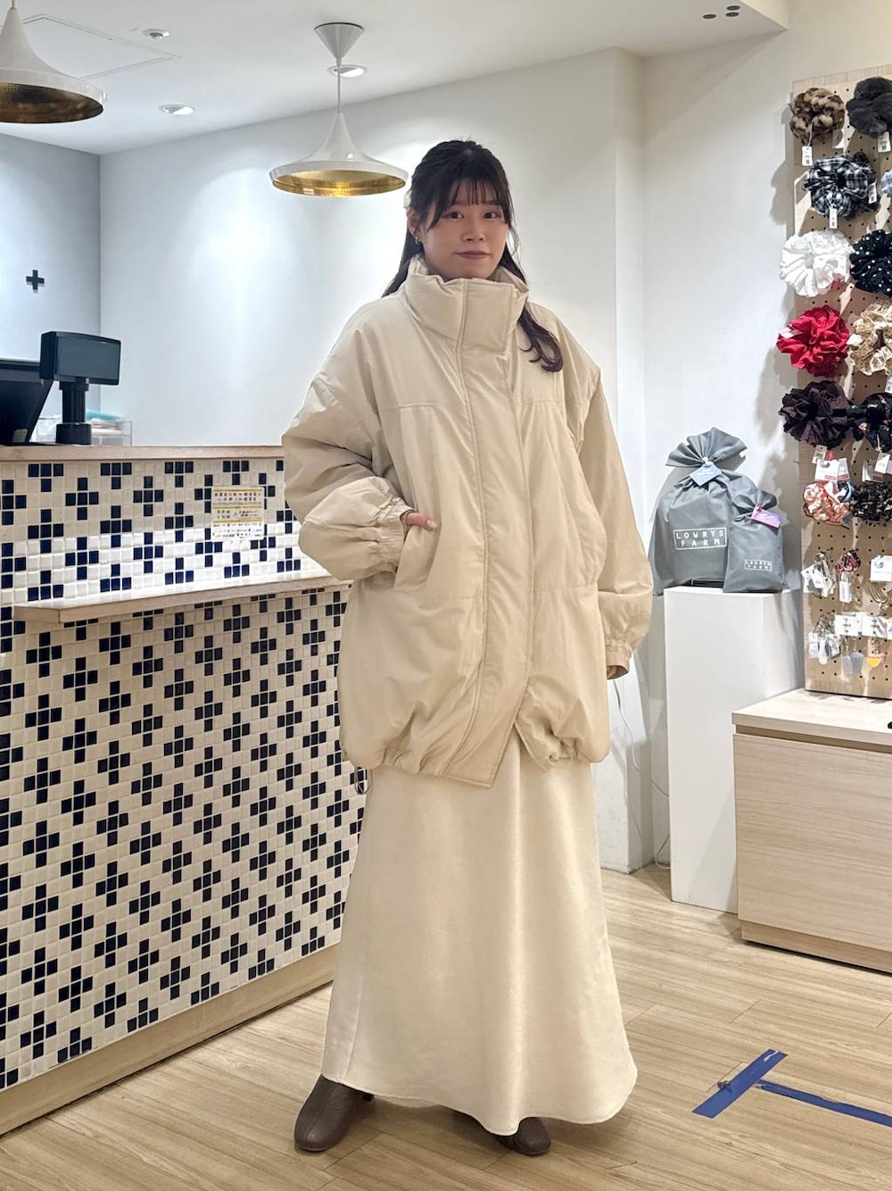 ホワイト系のスカート、ベージュ系のカーディガン/ボレロ、ブラウン系のブーツを着用したレディースの冬コーディネートの1枚目の写真