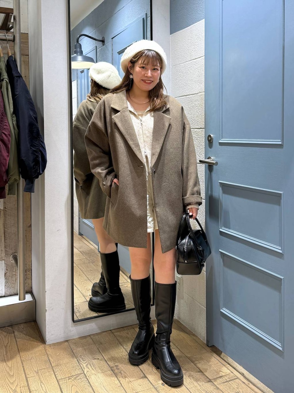 ブラウン系のチェスターコート、ホワイト系のその他パンツ、ブラック系のブーツを着用したレディースの秋コーディネートの1枚目の写真