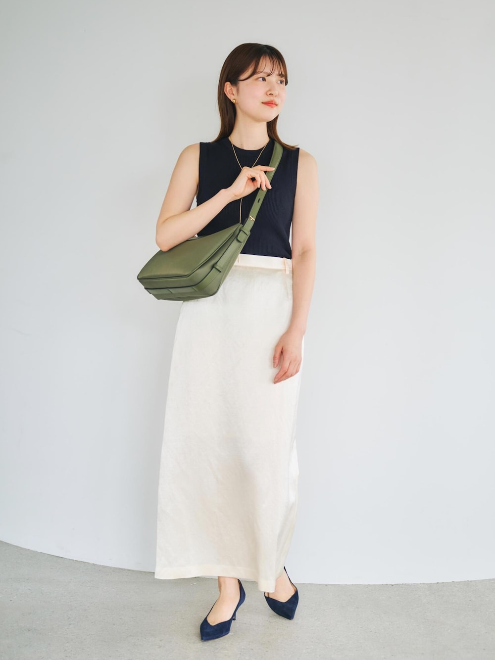 ブルー系のニット/セーター、グリーン系のハンドバッグ、ホワイト系のスカートを着用したレディースの春コーディネートの1枚目の写真