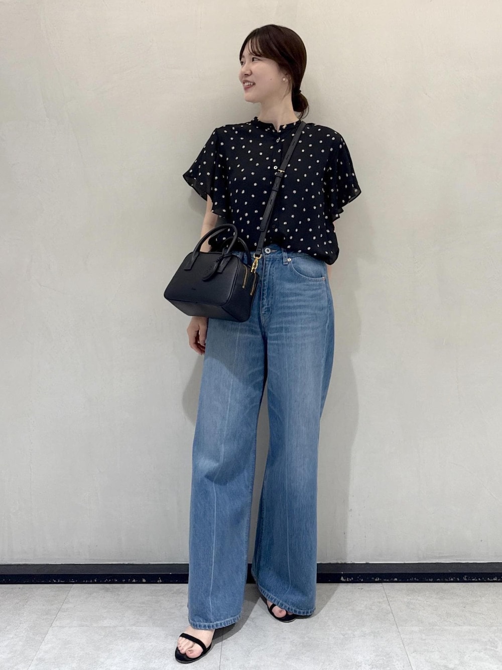 ブルー系のデニムパンツ、ブラック系のシャツ/ブラウス、ブラック系のハンドバッグを着用したレディースの夏コーディネートの1枚目の写真