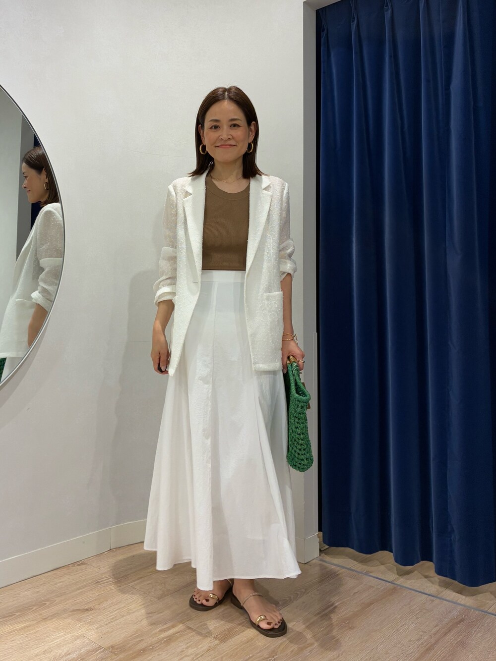 ブラウン系のタンクトップ、ホワイト系のテーラードジャケット、ホワイト系のスカートを着用したレディースの春コーディネートの1枚目の写真