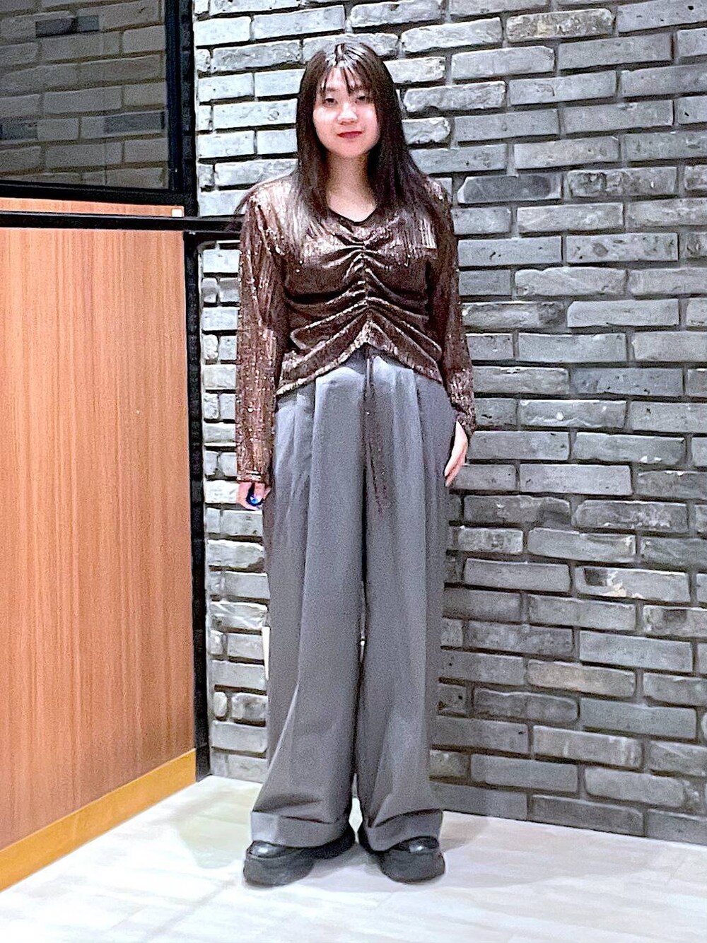 ブラック系のスニーカー、グレー系のスラックス、ブラウン系のTシャツ/カットソーを着用したレディースの夏コーディネートの1枚目の写真