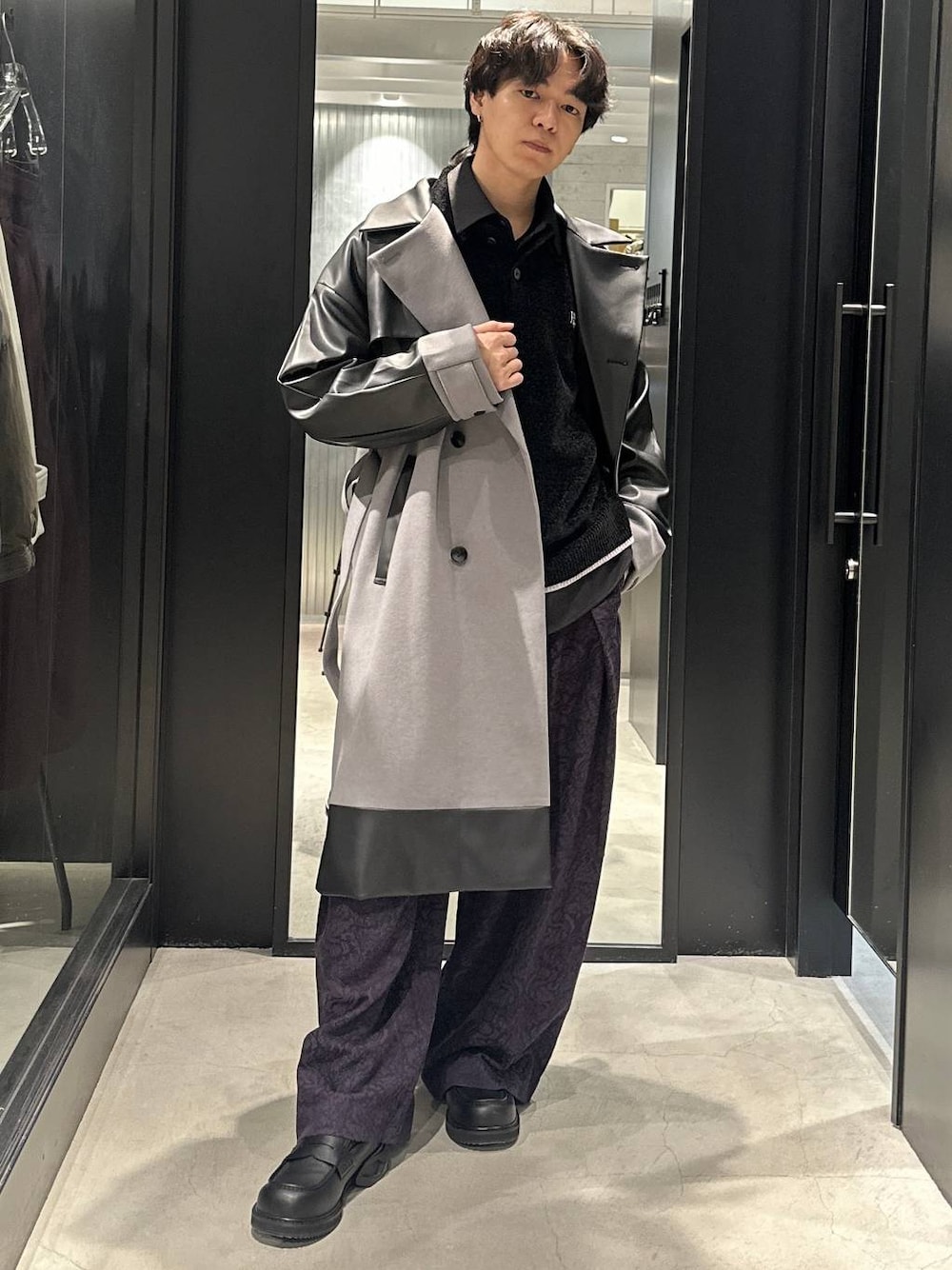 グレー系のトレンチコート、ブラック系のローファー、ブラック系のニット/セーターを着用したメンズの秋コーディネートの1枚目の写真