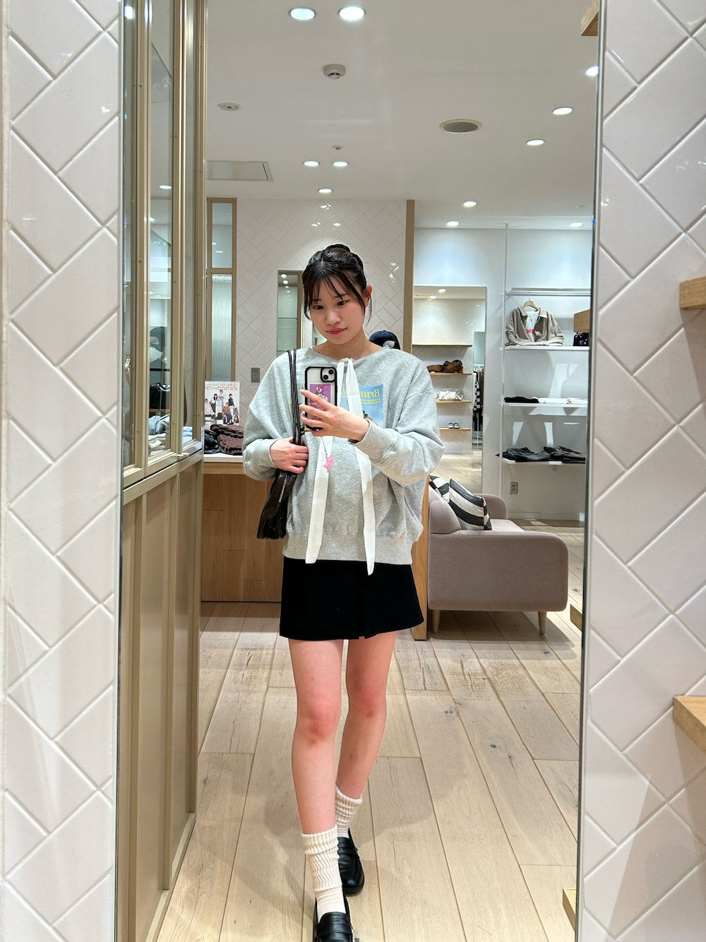 グレー系のスウェット、ホワイト系のシャツ/ブラウス、ブラック系のスカートを着用したレディースの秋コーディネートの1枚目の写真