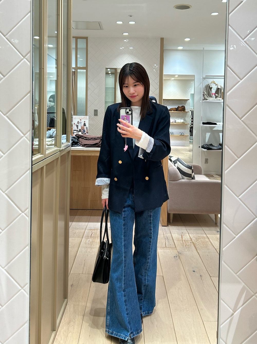 ブルー系のテーラードジャケット、ブルー系のデニムパンツ、ブラック系のショルダーバッグを着用したレディースの秋コーディネートの1枚目の写真