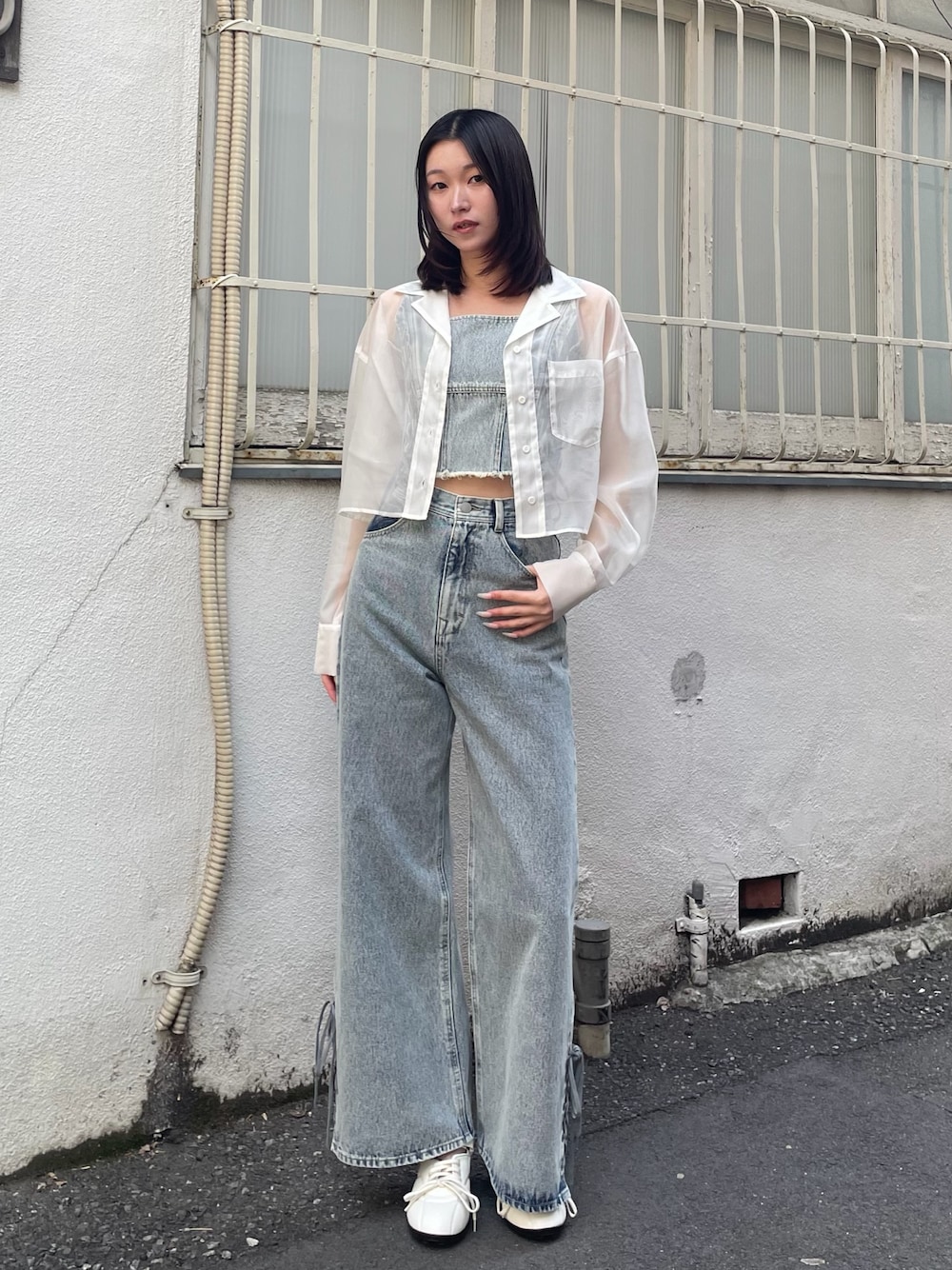 ブルー系のタンクトップ、ブルー系のデニムパンツ、ホワイト系のスニーカーを着用したレディースの春コーディネートの1枚目の写真