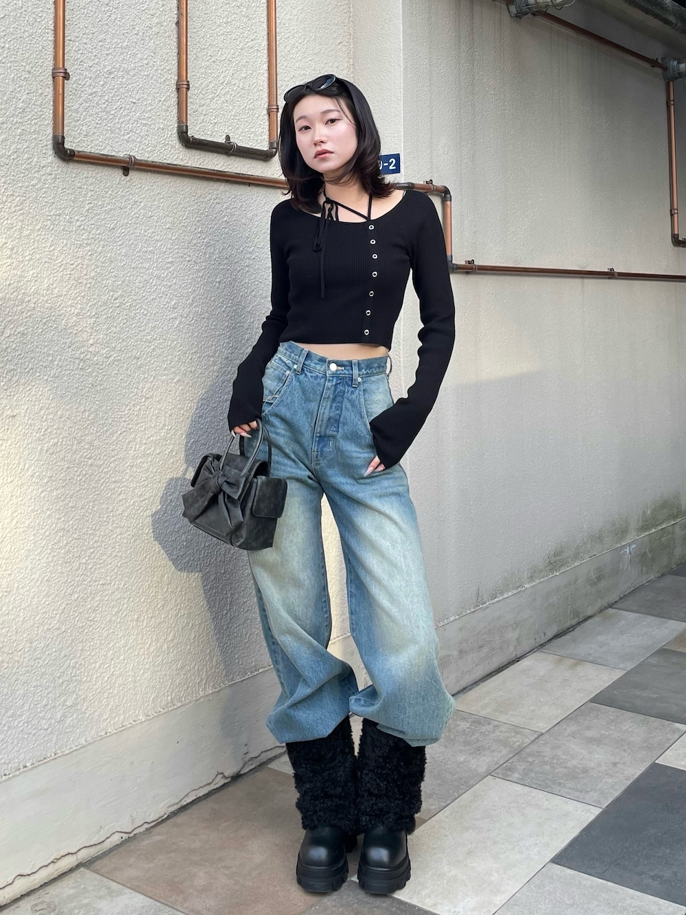 ブラック系のニット/セーター、ブルー系のデニムパンツ、ブラック系のブーツを着用したレディースの冬コーディネートの1枚目の写真