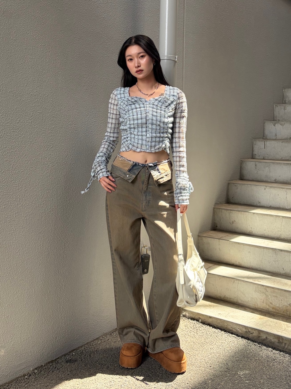 ブルー系のTシャツ/カットソー、ブラウン系のデニムパンツ、ホワイト系のハンドバッグを着用したレディースの秋コーディネートの1枚目の写真