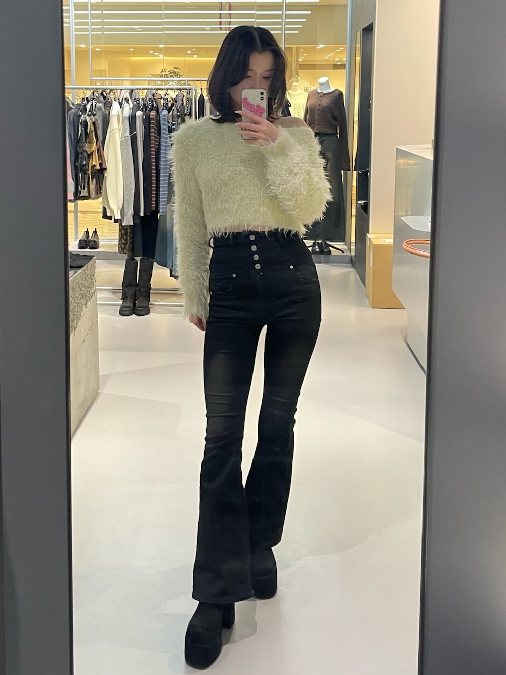 ホワイト系のニット/セーター、ブラック系のデニムパンツ、ブラック系のブーツを着用したレディースの冬コーディネートの1枚目の写真