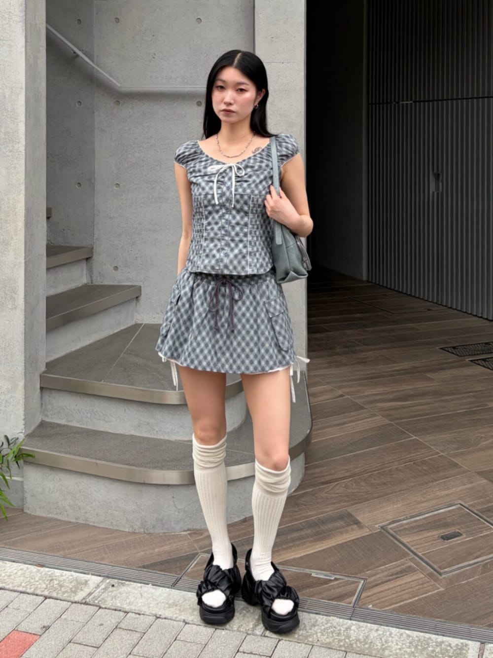 ブラック系のサンダル、ブルー系のハンドバッグ、ブルー系のシャツ/ブラウスを着用したレディースの夏コーディネートの1枚目の写真