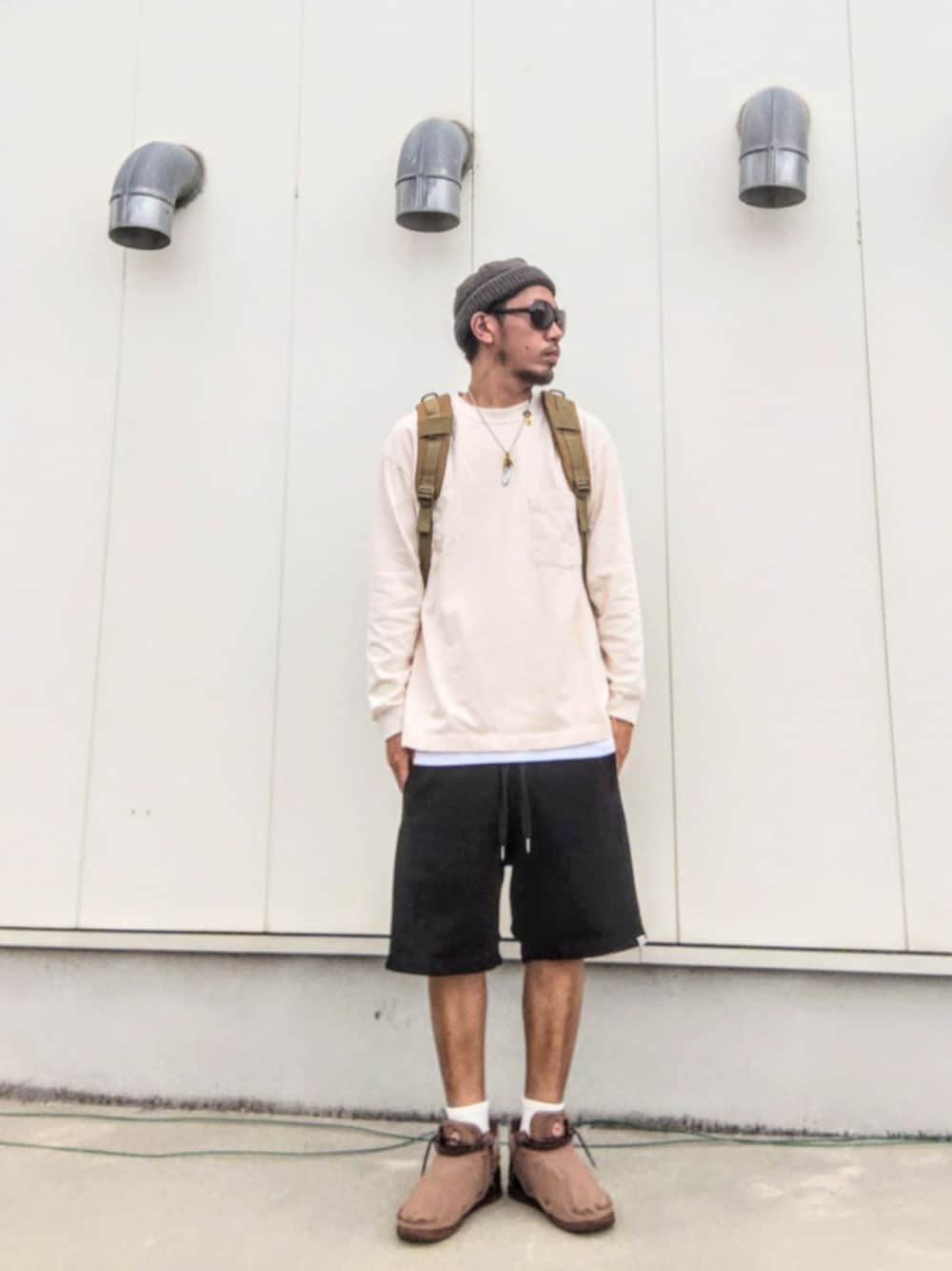ベージュ系のTシャツ/カットソー、ホワイト系のタンクトップ、グリーン系のバックパック/リュックを着用したメンズの秋コーディネートの1枚目の写真