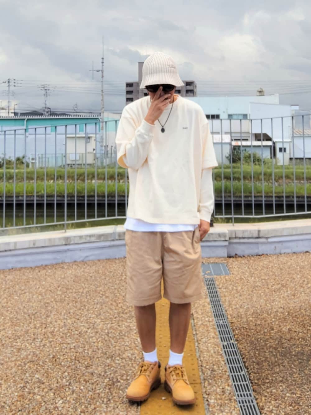 ホワイト系のTシャツ/カットソー、ホワイト系のタンクトップ、ベージュ系のチノパンツを着用したメンズの秋コーディネートの1枚目の写真