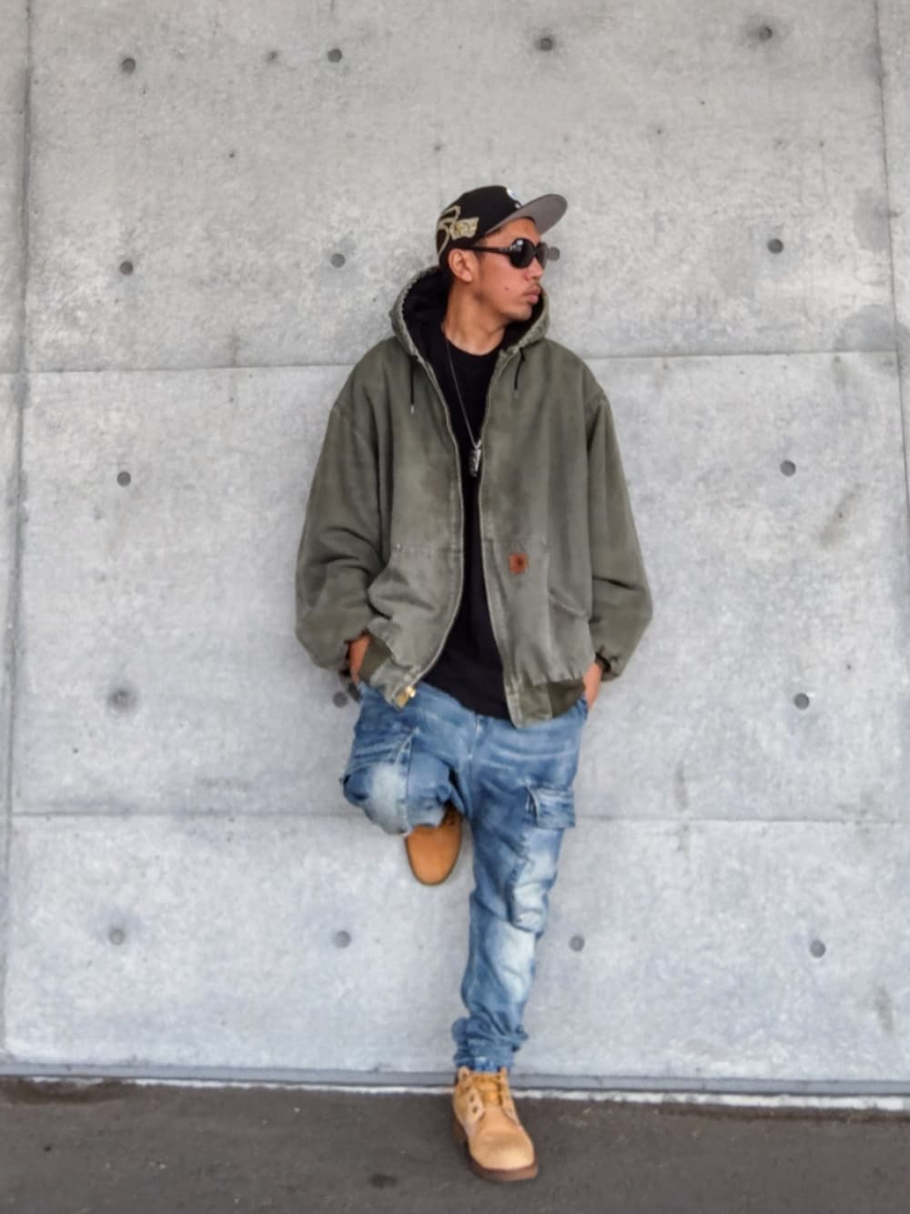 グリーン系のジャケット/アウター、ブラック系のTシャツ/カットソー、ブルー系のデニムパンツを着用したメンズの秋コーディネートの1枚目の写真