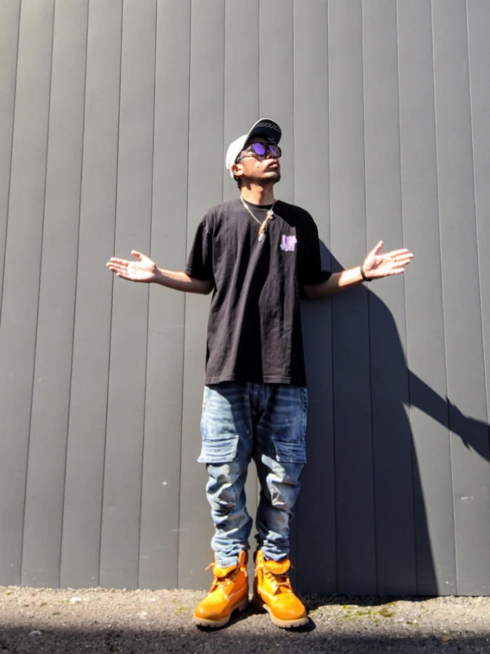 ブラック系のTシャツ/カットソー、ブルー系のデニムパンツ、イエロー系のブーツを着用したメンズの秋コーディネートの1枚目の写真