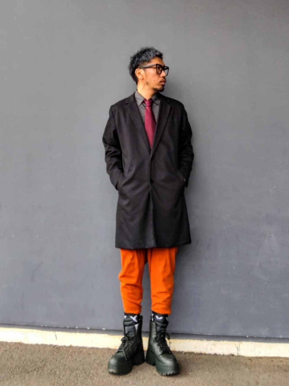 ブラック系のチェスターコート、ブラック系のシャツ/ブラウス、オレンジ系のその他パンツを着用したメンズの冬コーディネートの1枚目の写真