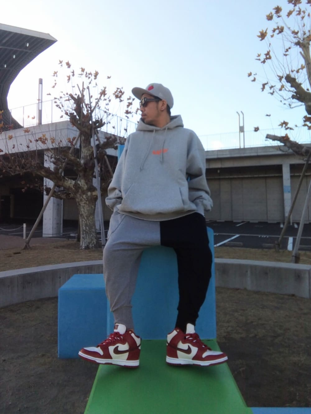 グレー系のパーカー、その他のスウェットパンツ、レッド系のスニーカーを着用したメンズの冬コーディネートの1枚目の写真