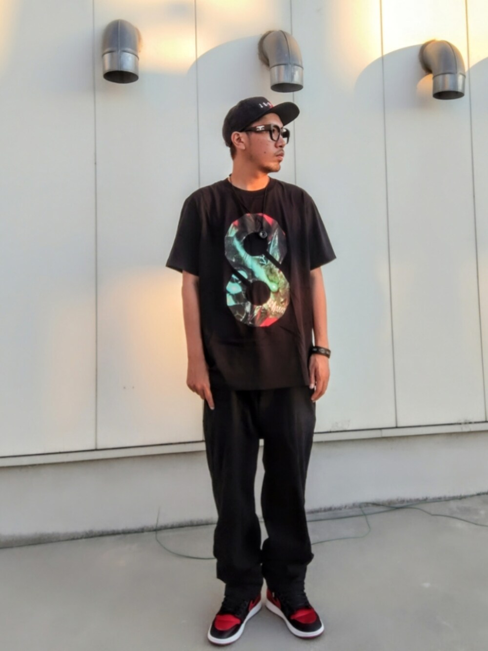 ブラック系のTシャツ/カットソー、ブラック系のデニムパンツ、ブラック系のスニーカーを着用したメンズの夏コーディネートの1枚目の写真