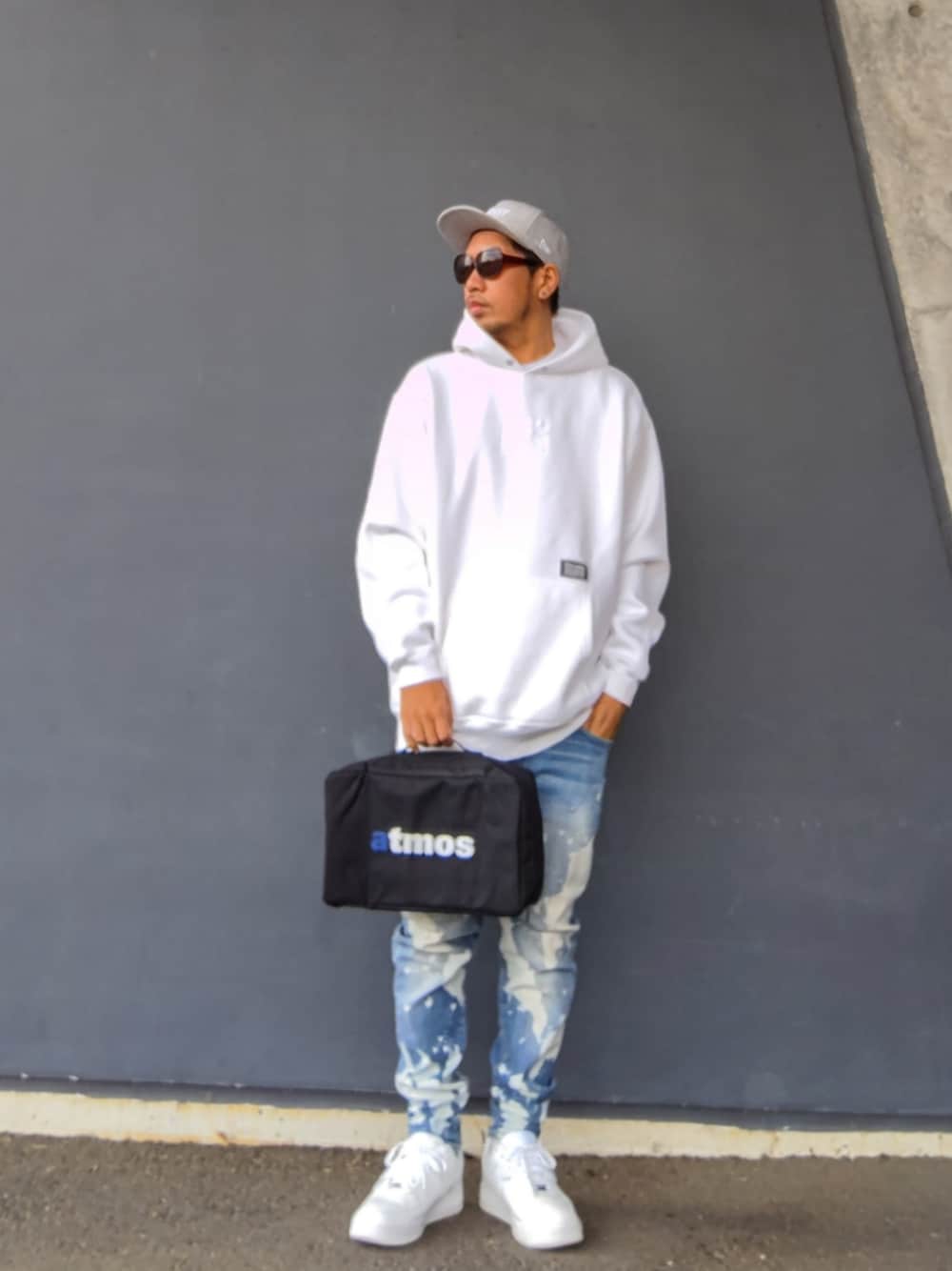 ホワイト系のパーカー、ブラック系のバッグ、ブルー系のデニムパンツを着用したメンズの冬コーディネートの1枚目の写真