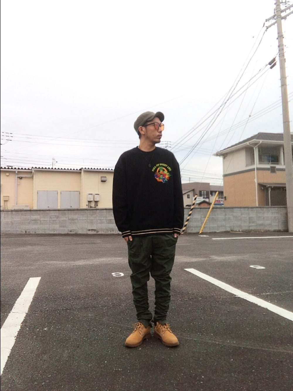 ブラック系のスウェット、グリーン系のパンツ、イエロー系のブーツを着用したメンズの秋コーディネートの1枚目の写真