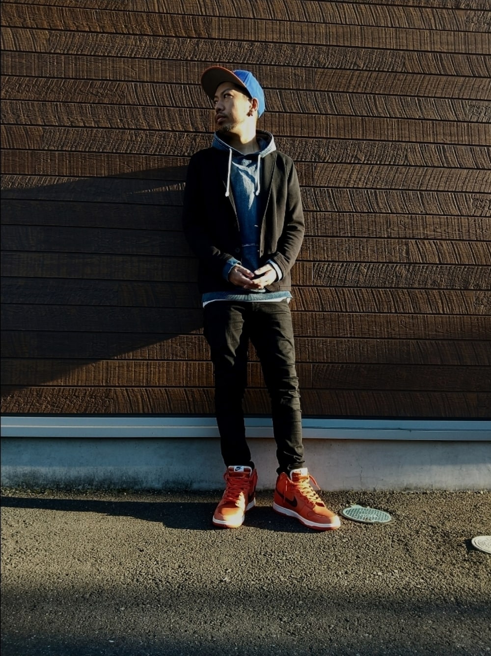 ブルー系のパーカー、ブラック系のデニムパンツ、オレンジ系のスニーカーを着用したメンズの秋コーディネートの1枚目の写真