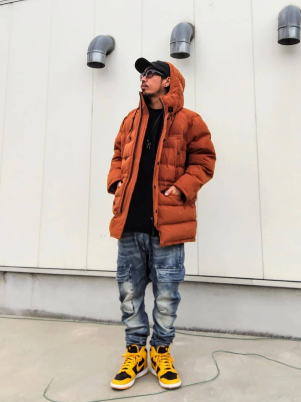 イエロー系のダウンジャケット/コート、ブラック系のTシャツ/カットソー、ブルー系のデニムパンツを着用したメンズの冬コーディネートの1枚目の写真