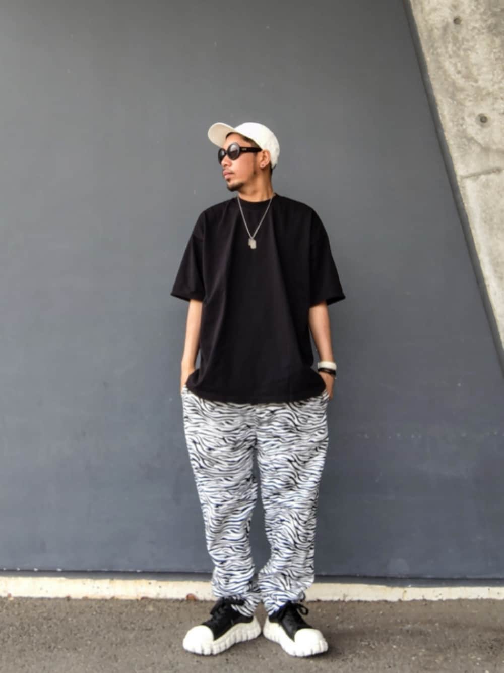 ブラック系のTシャツ/カットソー、ホワイト系のその他パンツ、その他のスニーカーを着用したメンズの春コーディネートの1枚目の写真