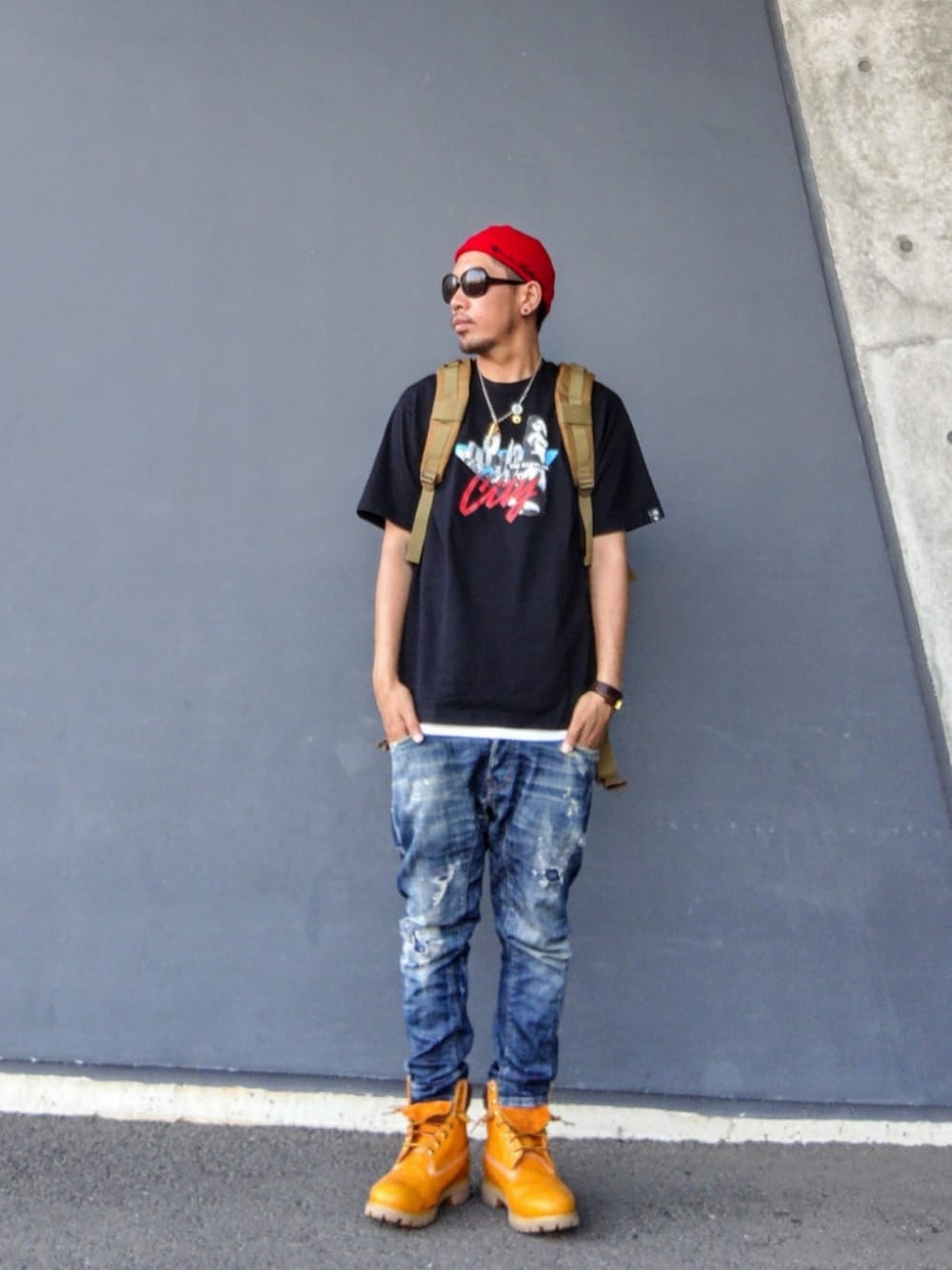 グリーン系のバックパック/リュック、ブラック系のTシャツ/カットソー、ブルー系のデニムパンツを着用したメンズの夏コーディネートの1枚目の写真