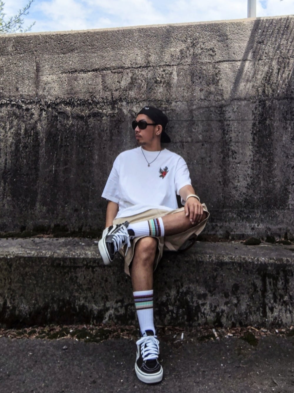 ホワイト系のTシャツ/カットソー、ベージュ系のカーゴパンツ、ブラック系のスニーカーを着用したメンズの夏コーディネートの1枚目の写真