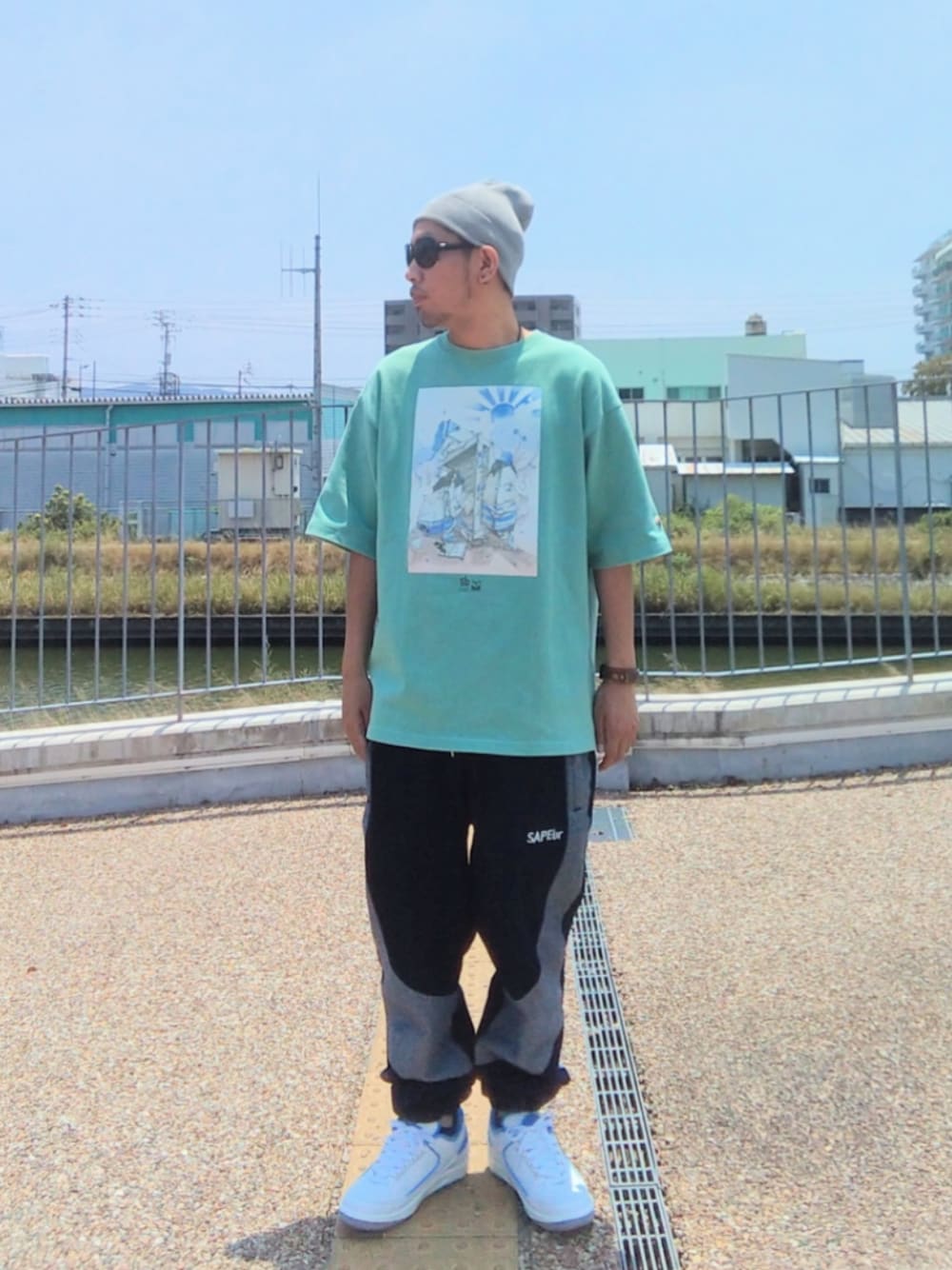 グリーン系のTシャツ/カットソー、ブルー系のデニムパンツ、ホワイト系のスニーカーを着用したメンズの夏コーディネートの1枚目の写真