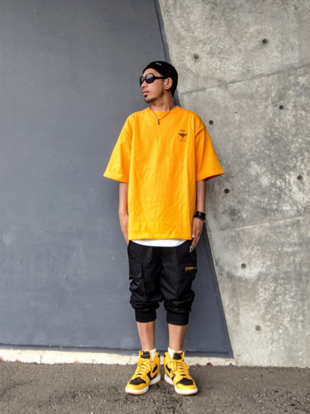 イエロー系のTシャツ/カットソー、ブラック系のカーゴパンツ、イエロー系のスニーカーを着用したメンズの夏コーディネートの1枚目の写真