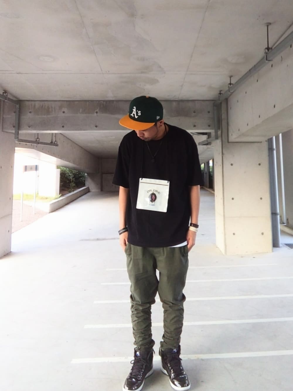 ブラック系のTシャツ/カットソー、グリーン系のパンツ、ブラック系のスニーカーを着用したメンズの夏コーディネートの1枚目の写真