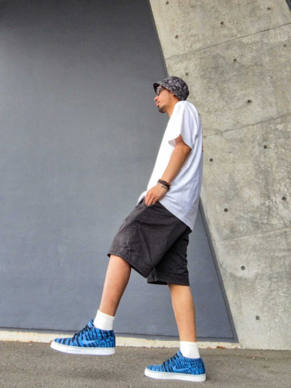 ホワイト系のTシャツ/カットソー、ブラック系のその他パンツ、ブルー系のスニーカーを着用したメンズの春コーディネートの1枚目の写真