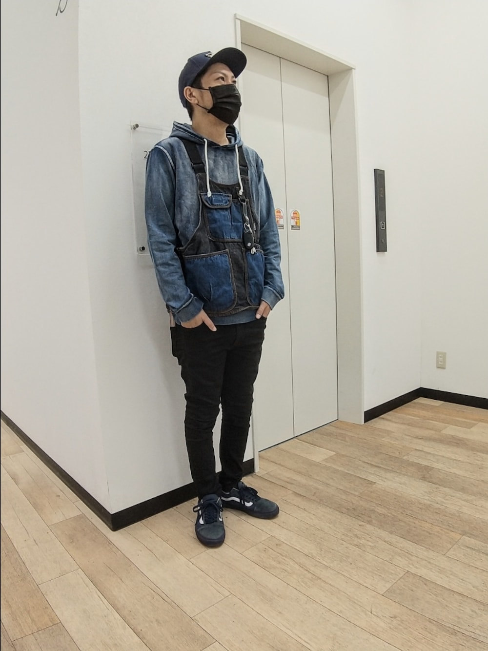 ブルー系のベスト、ブルー系のパーカー、ブラック系のデニムパンツを着用したメンズの秋コーディネートの1枚目の写真