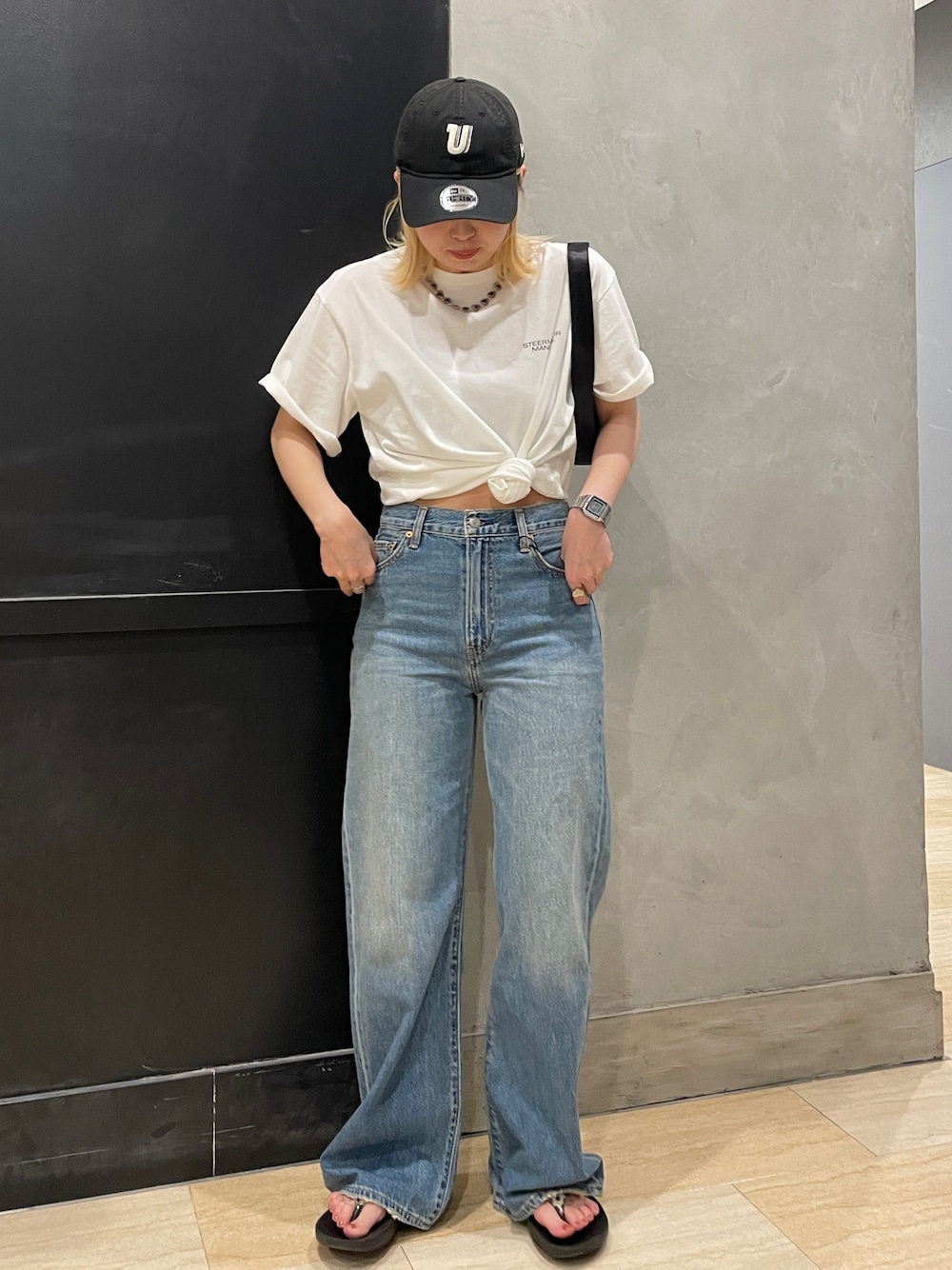 ブルー系のデニムパンツ、ホワイト系のTシャツ/カットソー、ブラック系のハンドバッグを着用したレディースの夏コーディネートの1枚目の写真