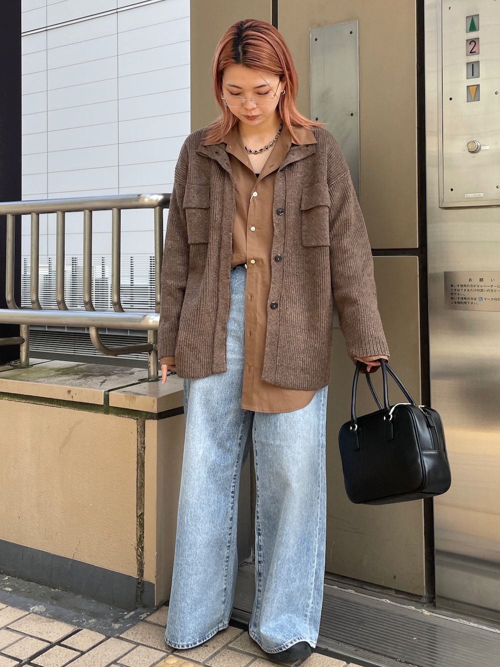ブラウン系のカーディガン/ボレロ、ブルー系のデニムパンツ、ブラック系のハンドバッグを着用したレディースの秋コーディネートの1枚目の写真