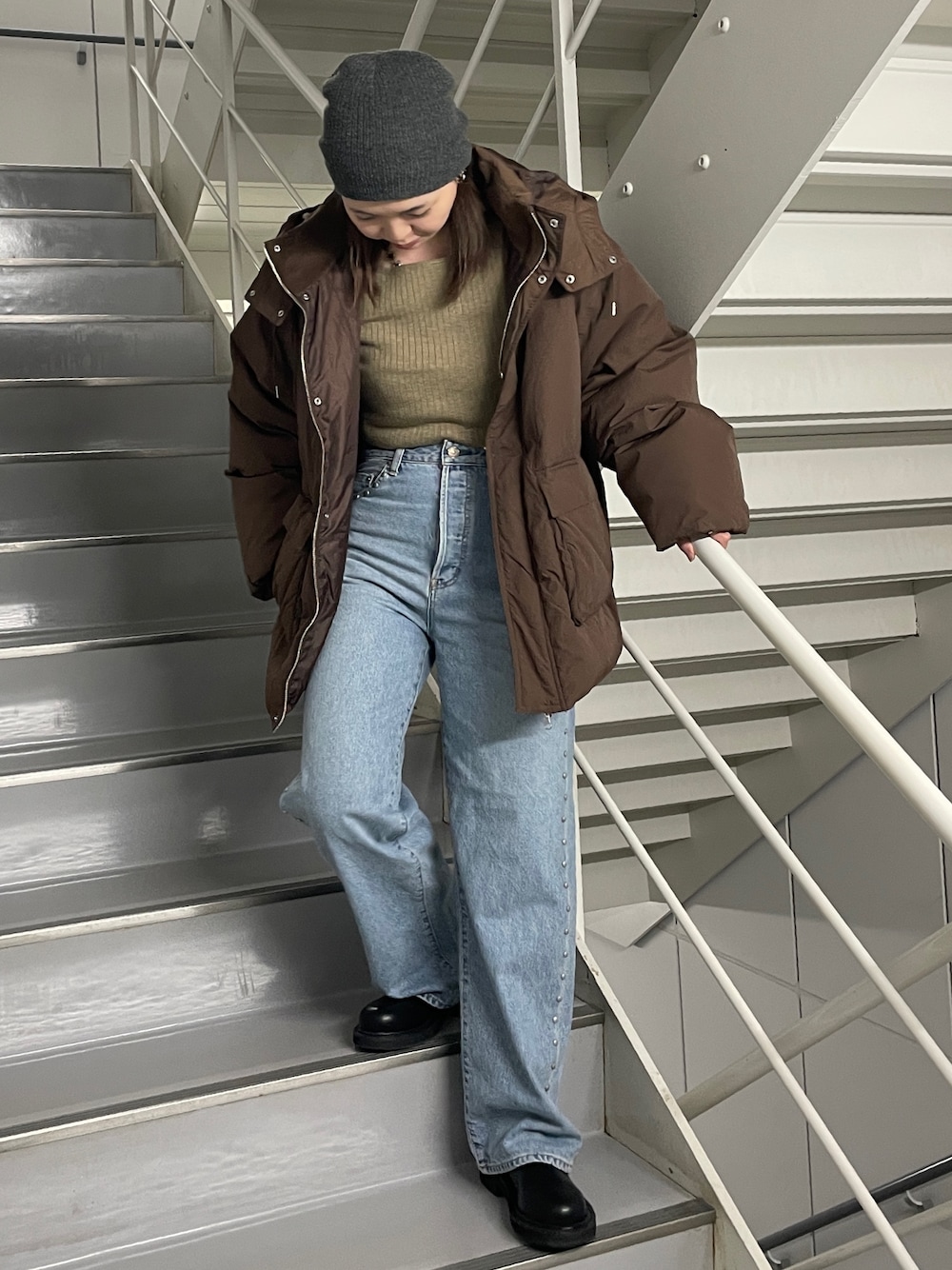 ブルー系のデニムパンツ、ブラック系のブーツ、ブラウン系のダウンジャケット/コートを着用したレディースの秋コーディネートの1枚目の写真